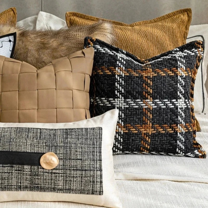 Housse Coussin Carreaux Noir et Blanc texturé avec un motif tartan en noir, blanc, marron, et orange, sur fond blanc - mis en scène sur un lit avec d'autres coussins