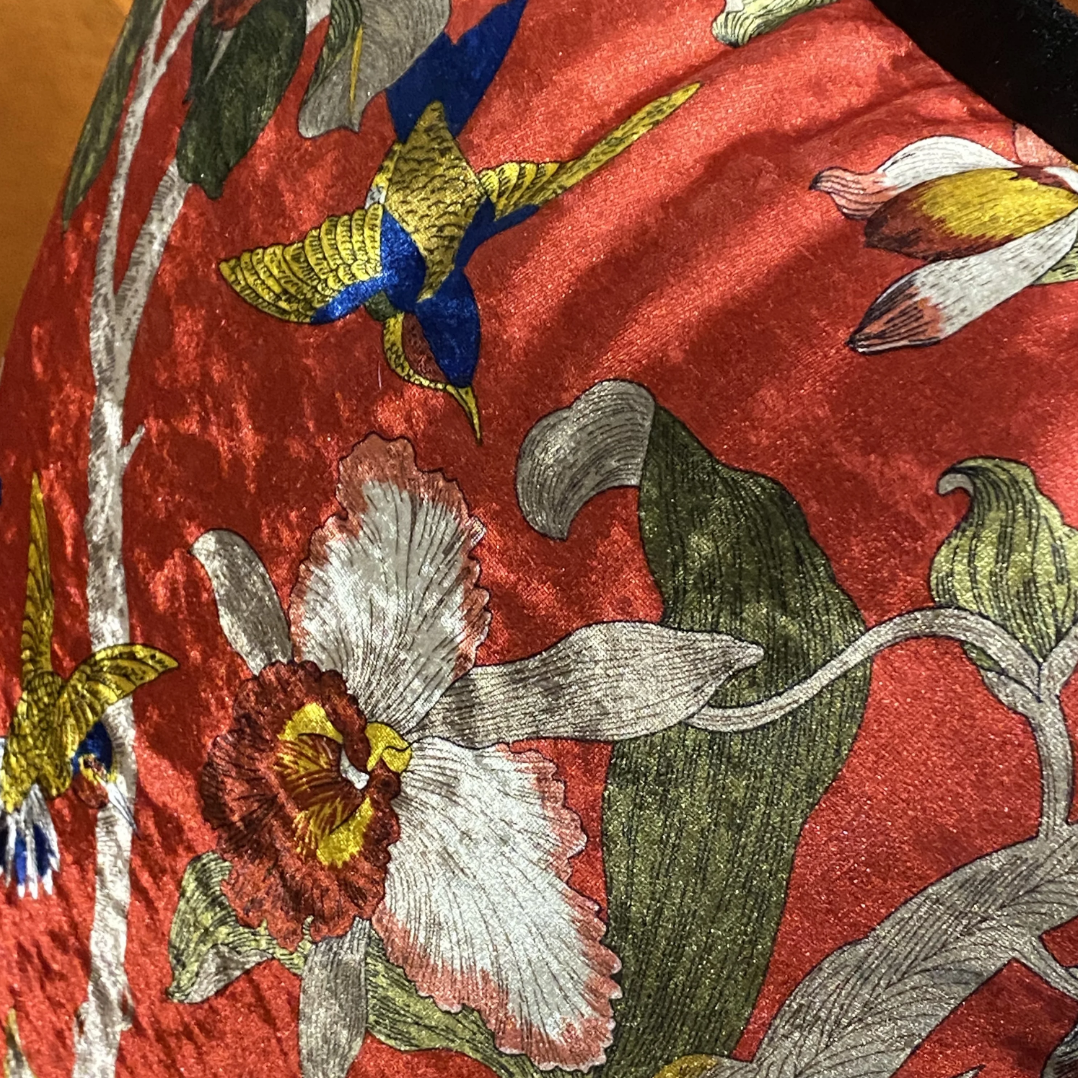 Housse de Coussin Boheme Fleur avec un fond rouge et des motifs floraux colorés, incluant des oiseaux colorés - zoom sur matière