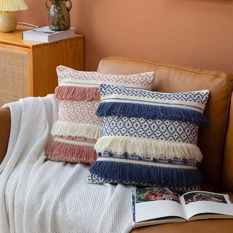 Housse de Coussin Rose Blanc décoratif de style boho chic avec motif tissé en rose et blanc et trois franges horizontales - mis en scène sur canapé cuir avec version bleu