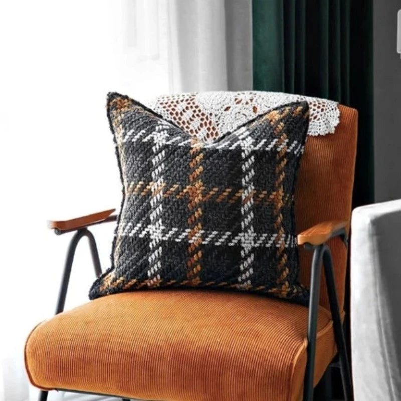 Housse Coussin Carreaux Noir et Blanc texturé avec un motif tartan en noir, blanc, marron, et orange, sur fond blanc - mis en scène sur fauteuil orange