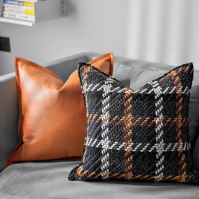 Housse Coussin Carreaux Noir et Blanc texturé avec un motif tartan en noir, blanc, marron, et orange, sur fond blanc - mis en scène sur canapé gris 