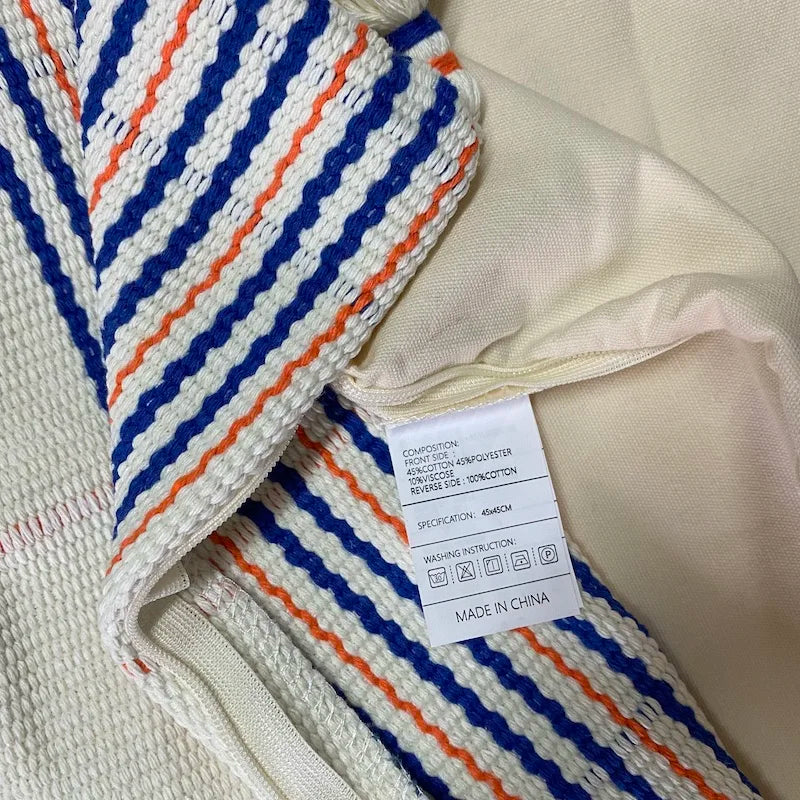 Housse de Coussin Blanc au Crochet avec lignes verticales bleues et orange et bandes horizontales en bas - zoom sur matière et etiquette