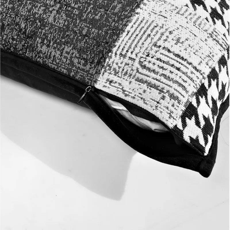 housses de coussin patchwork moderne gris écoratif moderne avec un design en patchwork noir et blanc comprenant des motifs comme des chevrons, des carreaux et des textures tissées, bordé par un liseré noir. Photographié sur un fond blanc avec un éclairage doux mettant en valeur les détails et les contrastes. - zoom sur fermeture