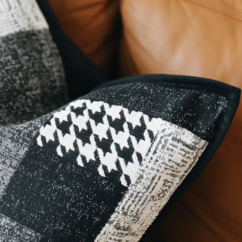 housses de coussin patchwork moderne gris écoratif moderne avec un design en patchwork noir et blanc comprenant des motifs comme des chevrons, des carreaux et des textures tissées, bordé par un liseré noir. Photographié sur un fond blanc avec un éclairage doux mettant en valeur les détails et les contrastes. - zoom sur matière