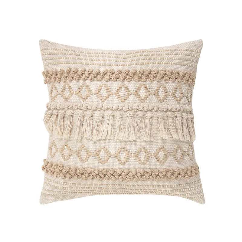 Housse de Coussin Coton Lin 45x45 style bohème avec des motifs tissés en losanges, des franges et des pompons, dans des tons neutres beige et écru, sur un fond blanc - de face