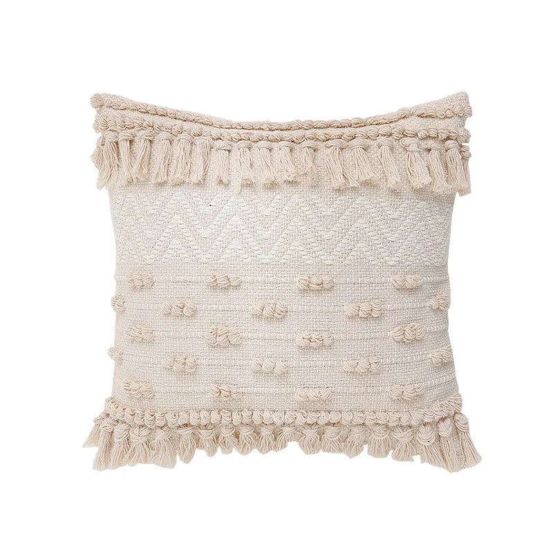 Housse de Coussin Coton Lin 45x45 style bohème avec des motifs tissés en losanges, des franges et des pompons, dans des tons neutres beige et écru, sur un fond blanc - de face modèle 2