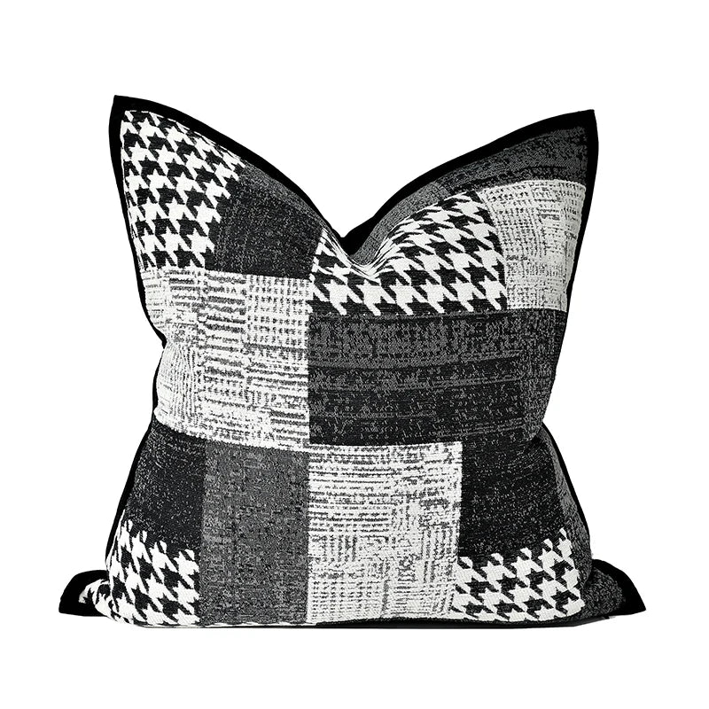 housses de coussin patchwork moderne gris écoratif moderne avec un design en patchwork noir et blanc comprenant des motifs comme des chevrons, des carreaux et des textures tissées, bordé par un liseré noir. Photographié sur un fond blanc avec un éclairage doux mettant en valeur les détails et les contrastes.- de face