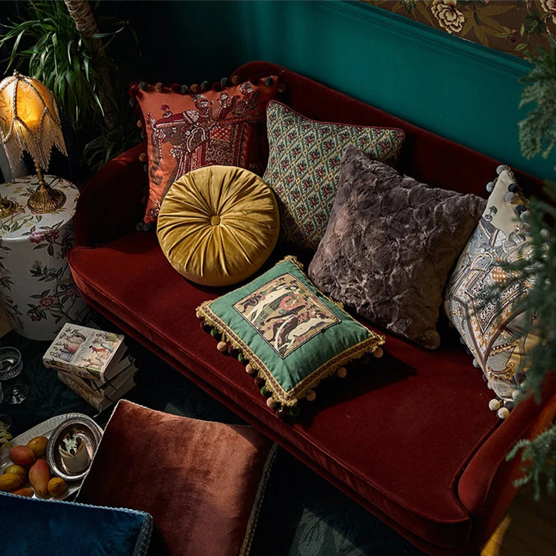 housse de coussin gris fourrure avec une texture douce et pelucheuse, éclairage diffus mettant en valeur les détails. - sur canapé rouge avec d'autres coussin, photo en plongée