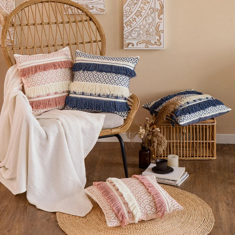 Housse de Coussin Rose Blanc décoratif de style boho chic avec motif tissé en rose et blanc et trois franges horizontales - mis en scène dans un style campagne avec version noire et bleu