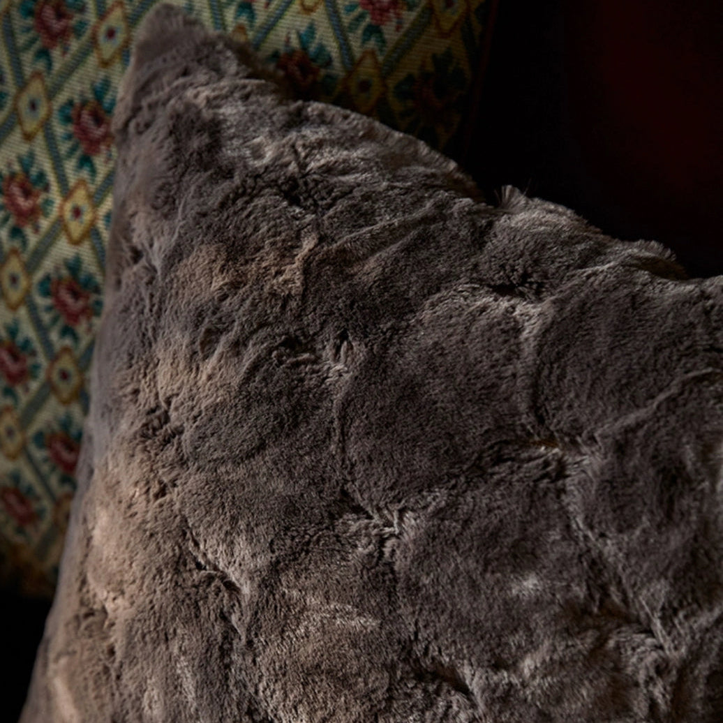 housse de coussin gris fourrure avec une texture douce et pelucheuse, éclairage diffus mettant en valeur les détails - zoom sur coin et matière