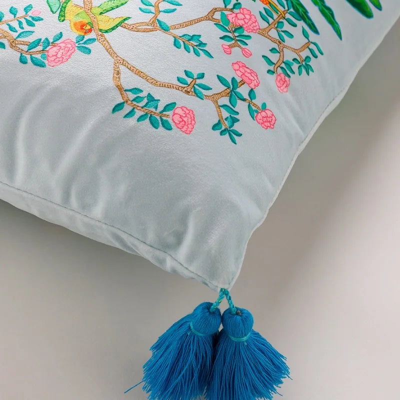 housse de coussin rectangulaire en velours avec motifs tropicaux avec des perroquets, des toucans, des léopards et des plantes luxuriantes, orné de pompons bleus - zoom sur coin