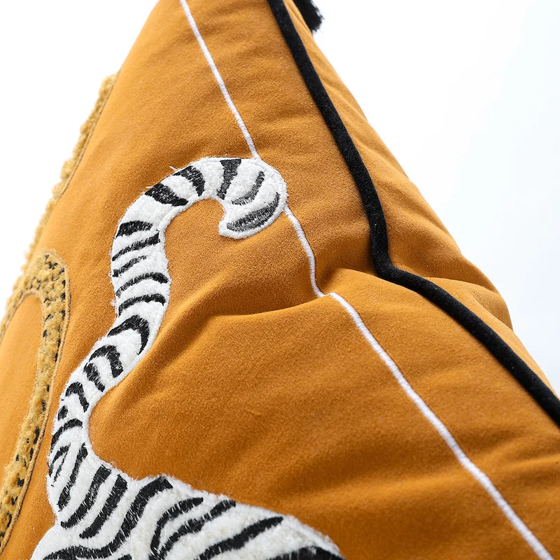 Housse de Coussin Moutarde et Noir décoratif avec broderie d'un tigre blanc et d'un léopard doré sur un fond jaune, orné de glands noirs aux coins - Zoom sur le passepoil