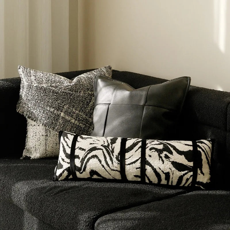 housse de coussin zebre 50x50 moderne avec un motif zèbre noir et blanc, comportant deux bandes horizontales noires au centre, sur un fond blanc - version rectangle mis en scène sur canapé noir