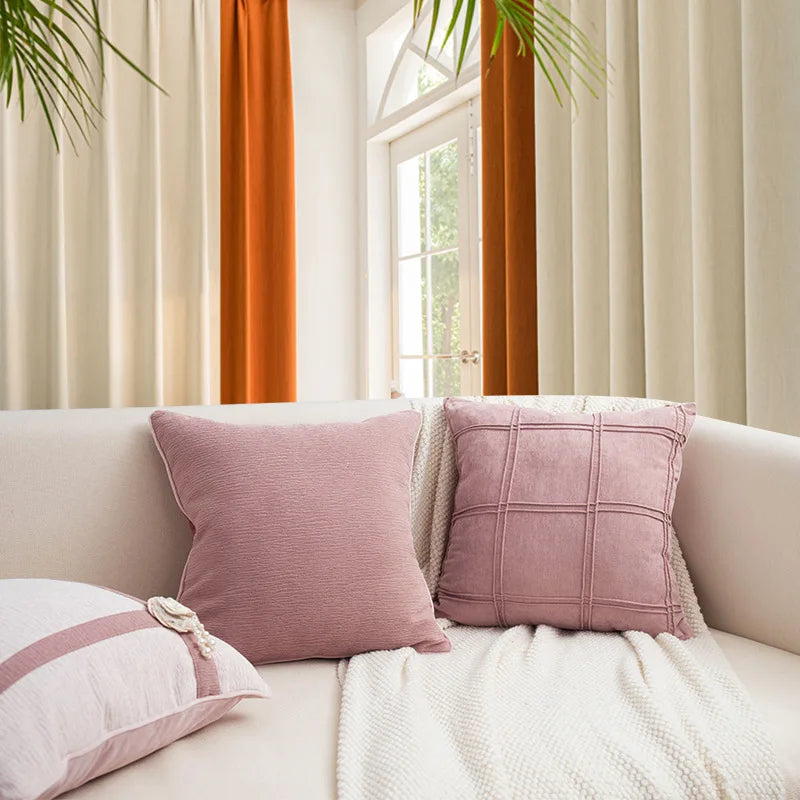 housse de coussin rose poudré avec une texture légèrement ondulée, présenté sur un fond clair et uni, éclairé par une lumière douce. - sur canapé