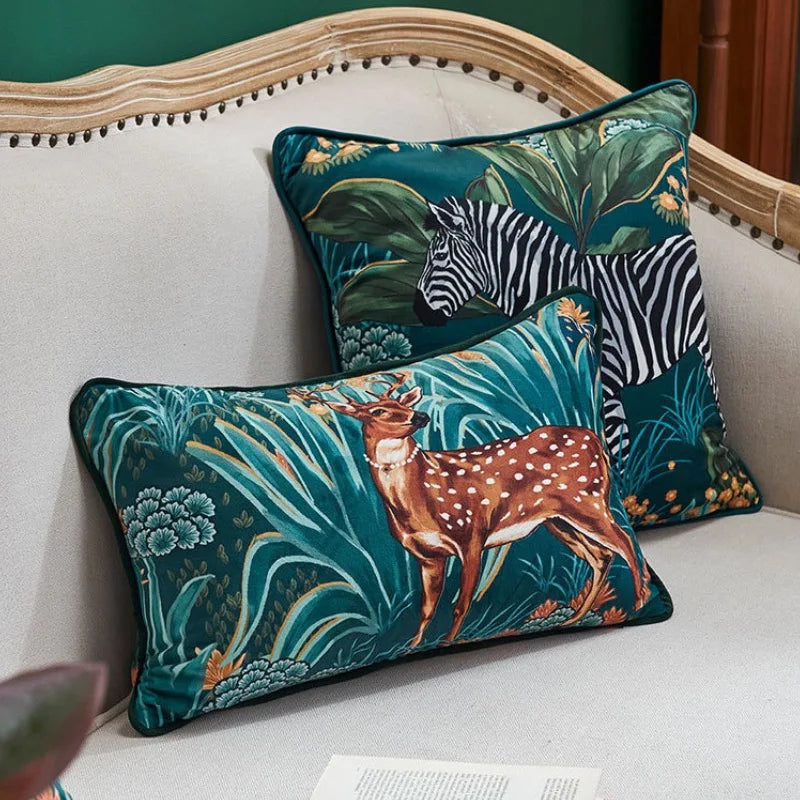 housse de coussin bleu canard floral avec un zèbre au milieu d'un feuillage tropical. Fond bleu-vert avec des feuilles vert foncé et des fleurs jaunes et blanches. Style artistique et détaillé - mis en scène sur canapé ivoire