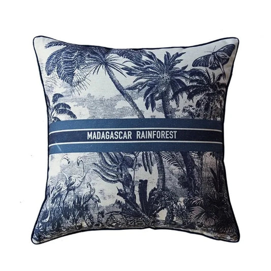 Housse de Coussin 45x45 avec Lettre représentant la forêt tropicale de Madagascar avec des palmiers, des flamants roses et un grand papillon. Le texte "MADAGASCAR RAINFOREST" est centré, encadré par deux lignes horizontales - de face