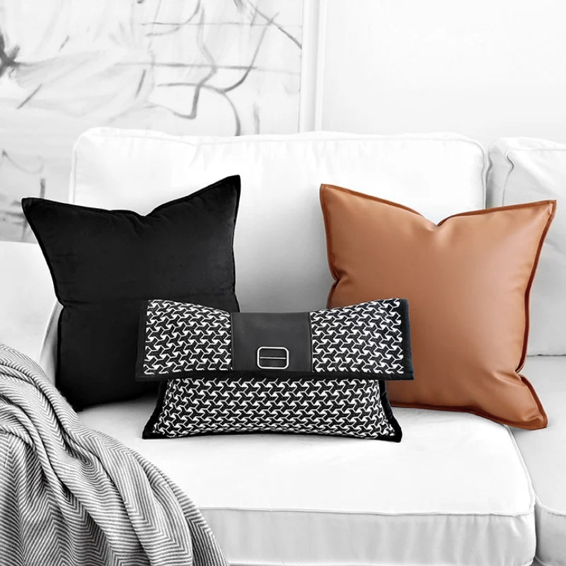 Housse de Coussin Rectangulaire Noir et Blanc En Forme de pochette élégante rectangulaire avec un motif en chevrons noir et blanc, un détail central en cuir noir et une boucle en métal argenté, posée sur un fond blanc minimaliste. - posée sur canapé avec deux autres coussins