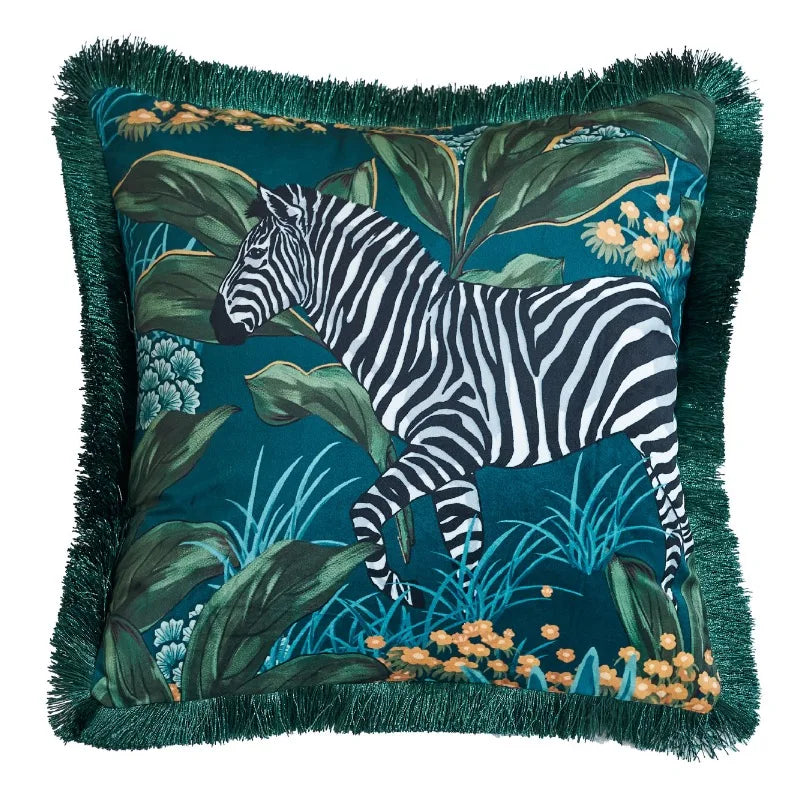 housse de coussin bleu canard floral avec un zèbre au milieu d'un feuillage tropical. Fond bleu-vert avec des feuilles vert foncé et des fleurs jaunes et blanches. Style artistique et détaillé - avec frange et de face