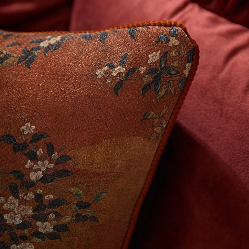 Housse de Coussin Fleur Japonais avec un motif floral traditionnel inspiré de l'Asie. Le coussin est marron avec des nuances plus claires et plus foncées créant un fond texturé. Le design présente des branches avec de petites fleurs blanches et des feuilles sombres dispersées sur le coussin. Le style général est élégant et classique - zoom sur matière