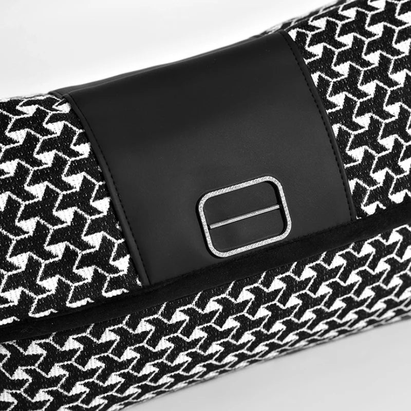 Housse de Coussin Rectangulaire Noir et Blanc En Forme de pochette élégante rectangulaire avec un motif en chevrons noir et blanc, un détail central en cuir noir et une boucle en métal argenté, posée sur un fond blanc minimaliste - zoom sur motif 