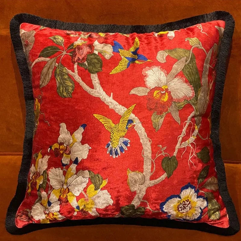 Housse de Coussin Boheme Fleur avec un fond rouge et des motifs floraux colorés, incluant des oiseaux colorés - en face et en scène