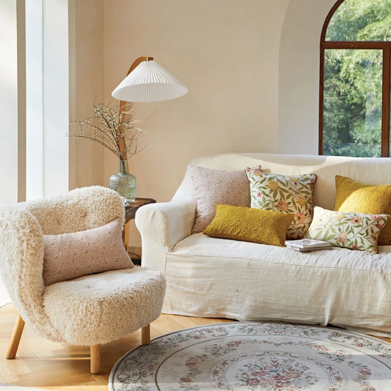 Housse de Coussin Jaune Moutarde Fleurs écoratif moderne avec un fond blanc et des motifs floraux en relief représentant des roses stylisées, photographié sur une surface blanche avec un éclairage doux pour mettre en valeur la texture et les détails - plan large du salon