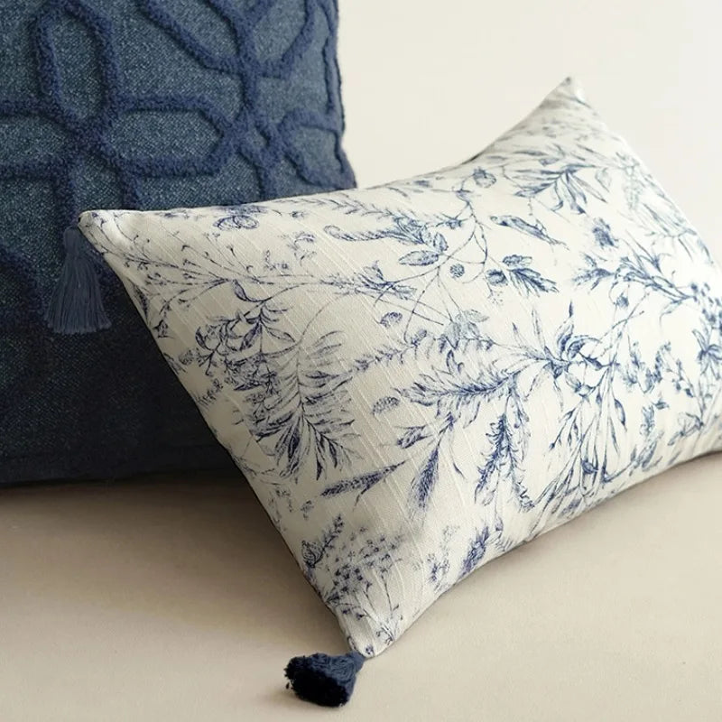 Housse de Coussin 45x45 Lin Blanc décoratif carré avec motifs floraux bleus sur fond blanc, agrémenté de pompons bleus aux quatre coins, présenté sur un arrière-plan clair et minimaliste - zoom sur version rectangle 