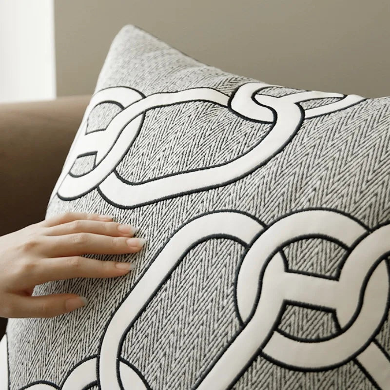 Housse de Coussin Couleur Blanc et gris clair avec motif de chaînes entrelacées blanches, sur fond à texture en chevrons - version chaines a broderie noire - zoom sur maière