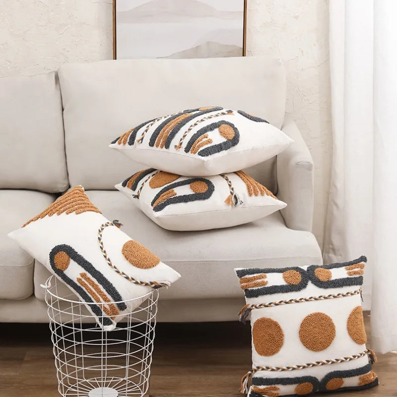 Housse de Coussin Style Boheme Terracotta décoratif au style bohème minimaliste, avec broderies en relief de formes géométriques jaunes moutarde et grises anthracite, sur fond blanc texturé. Bordures tressées artisanales - mis en scène sur canapé