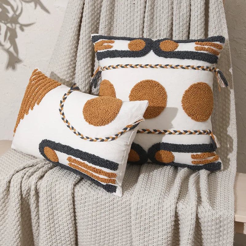 Housse de Coussin Style Boheme Terracotta décoratif au style bohème minimaliste, avec broderies en relief de formes géométriques jaunes moutarde et grises anthracite, sur fond blanc texturé. Bordures tressées artisanales - mis en scène avec version rectangulaire