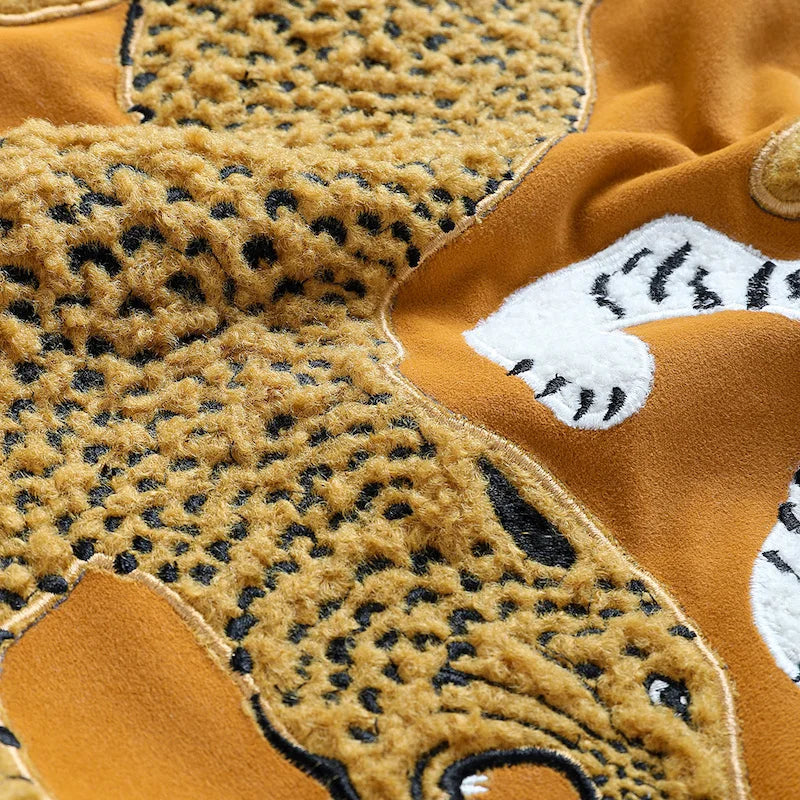 Housse de Coussin Moutarde et Noir décoratif avec broderie d'un tigre blanc et d'un léopard doré sur un fond jaune, orné de glands noirs aux coins - Zoom sur les textures