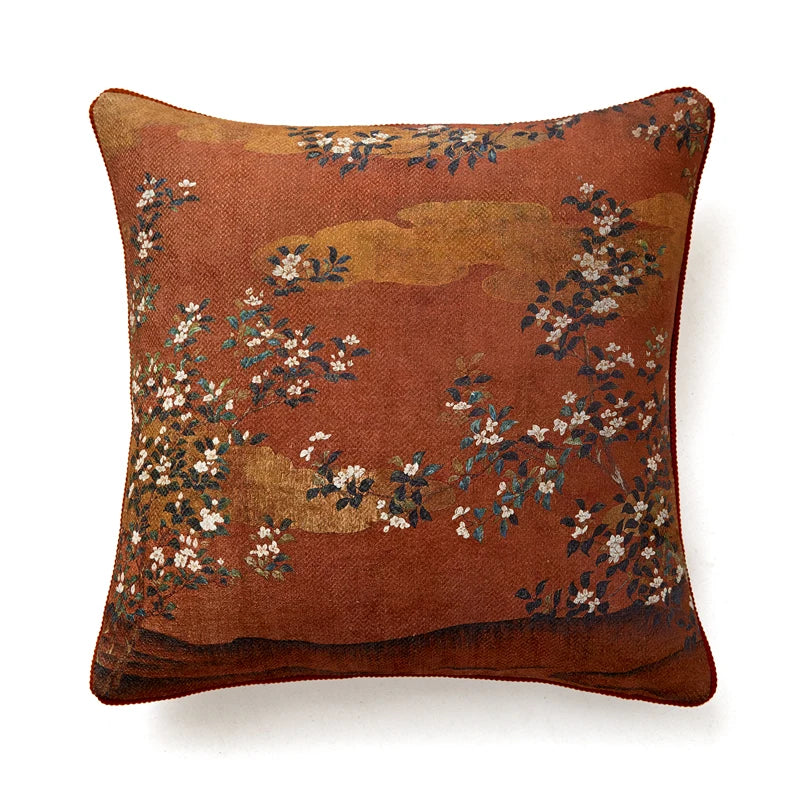 Housse de Coussin Fleur Japonais avec un motif floral traditionnel inspiré de l'Asie. Le coussin est marron avec des nuances plus claires et plus foncées créant un fond texturé. Le design présente des branches avec de petites fleurs blanches et des feuilles sombres dispersées sur le coussin. Le style général est élégant et classique - de face