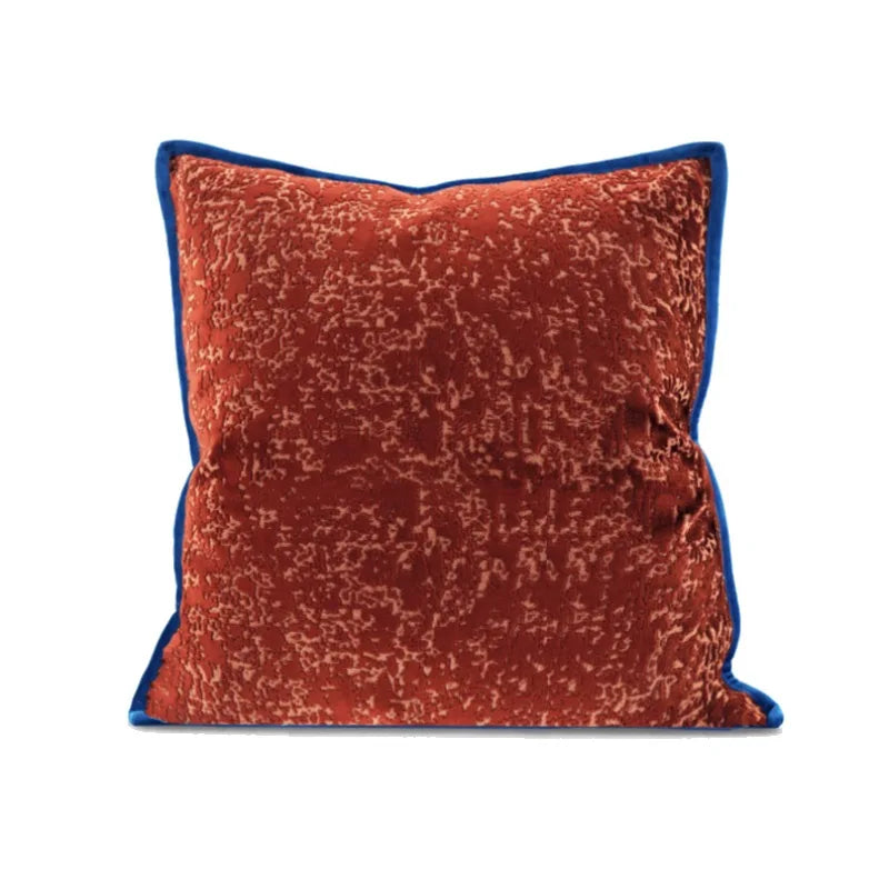 Coussin carré en tissu texturé rouge brique avec bordure bleue, motif irrégulier en relief. sur Fond blanc - de face